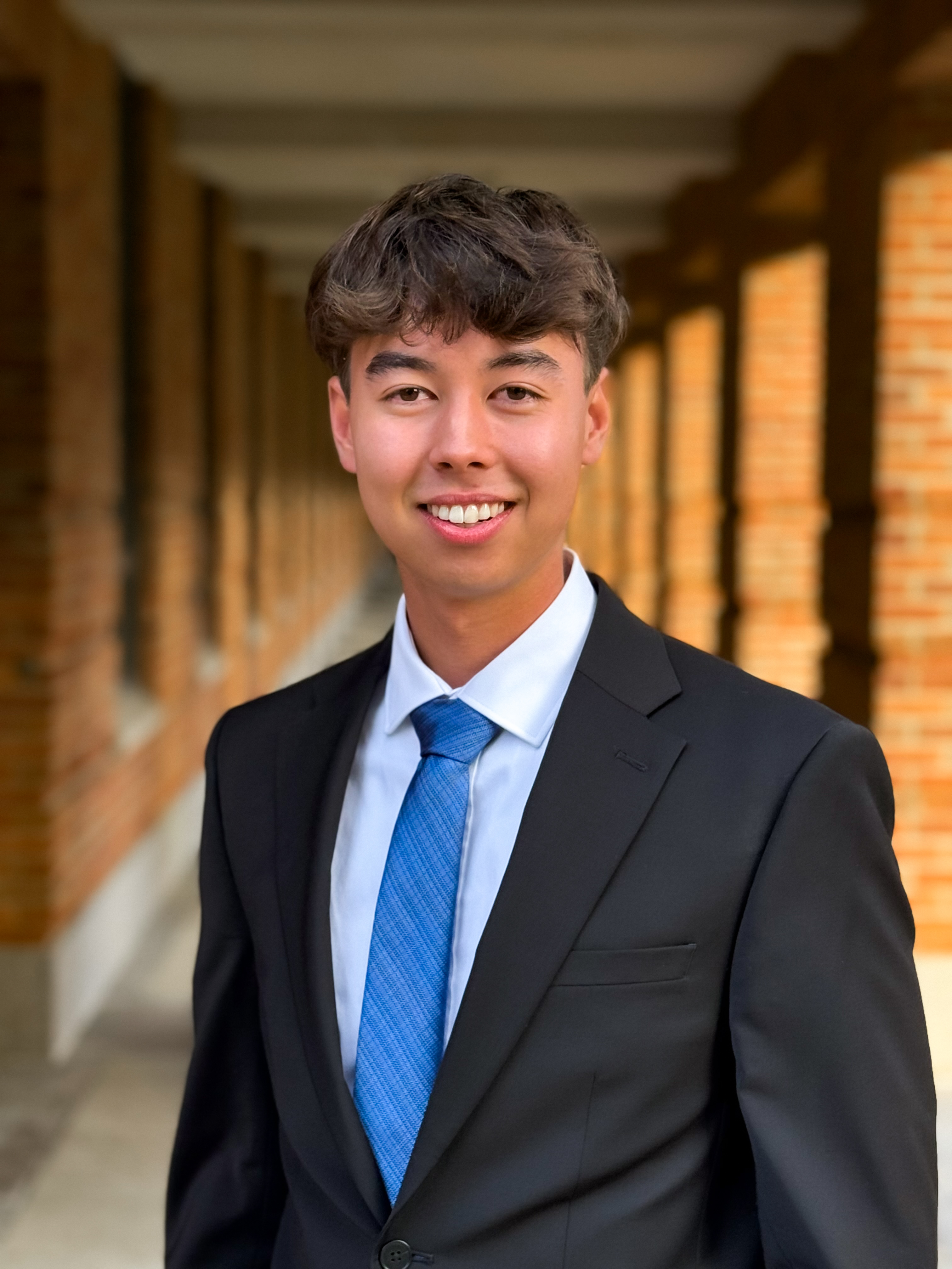 Man smiling at the camera with a black tux and blue tie