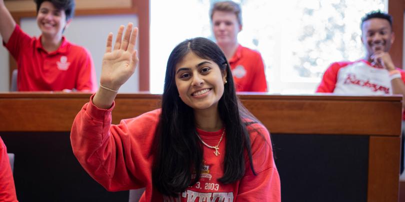 A student raises her hand in the classroom