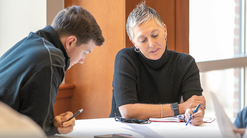 2 people discussing documents at a table