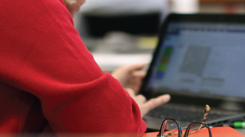 Someone working at a desk on their laptop