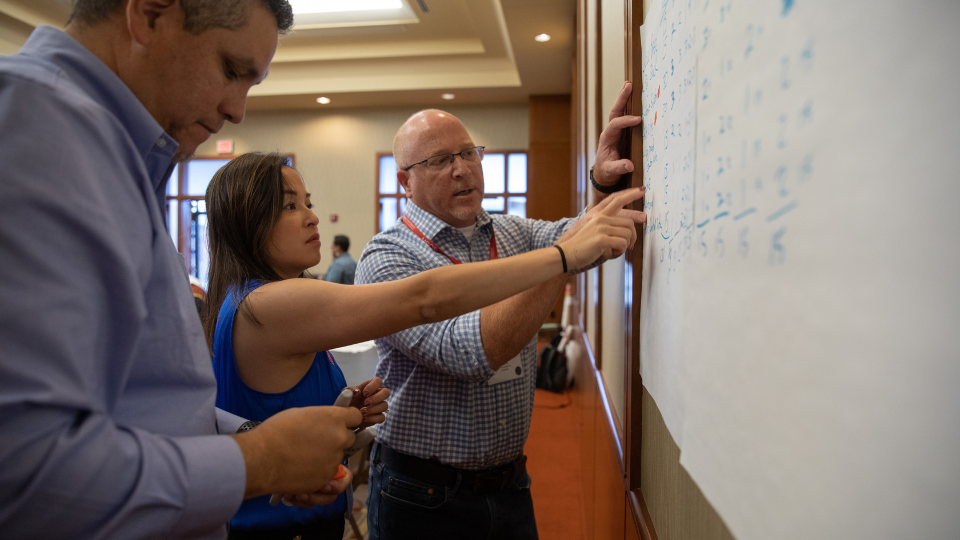 3 people at a whiteboard participating in a Lean Six Sigma activity
