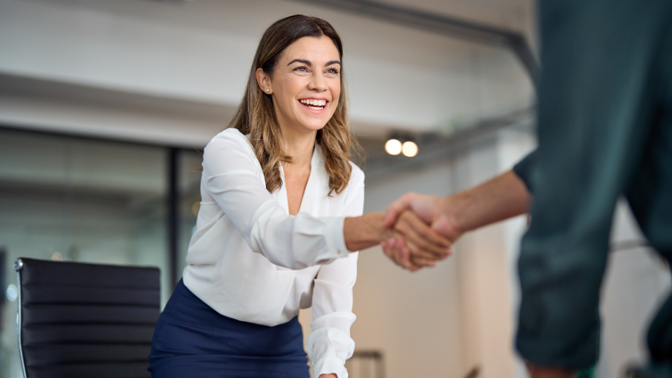 A woman and a man shaking hands in a business meeting