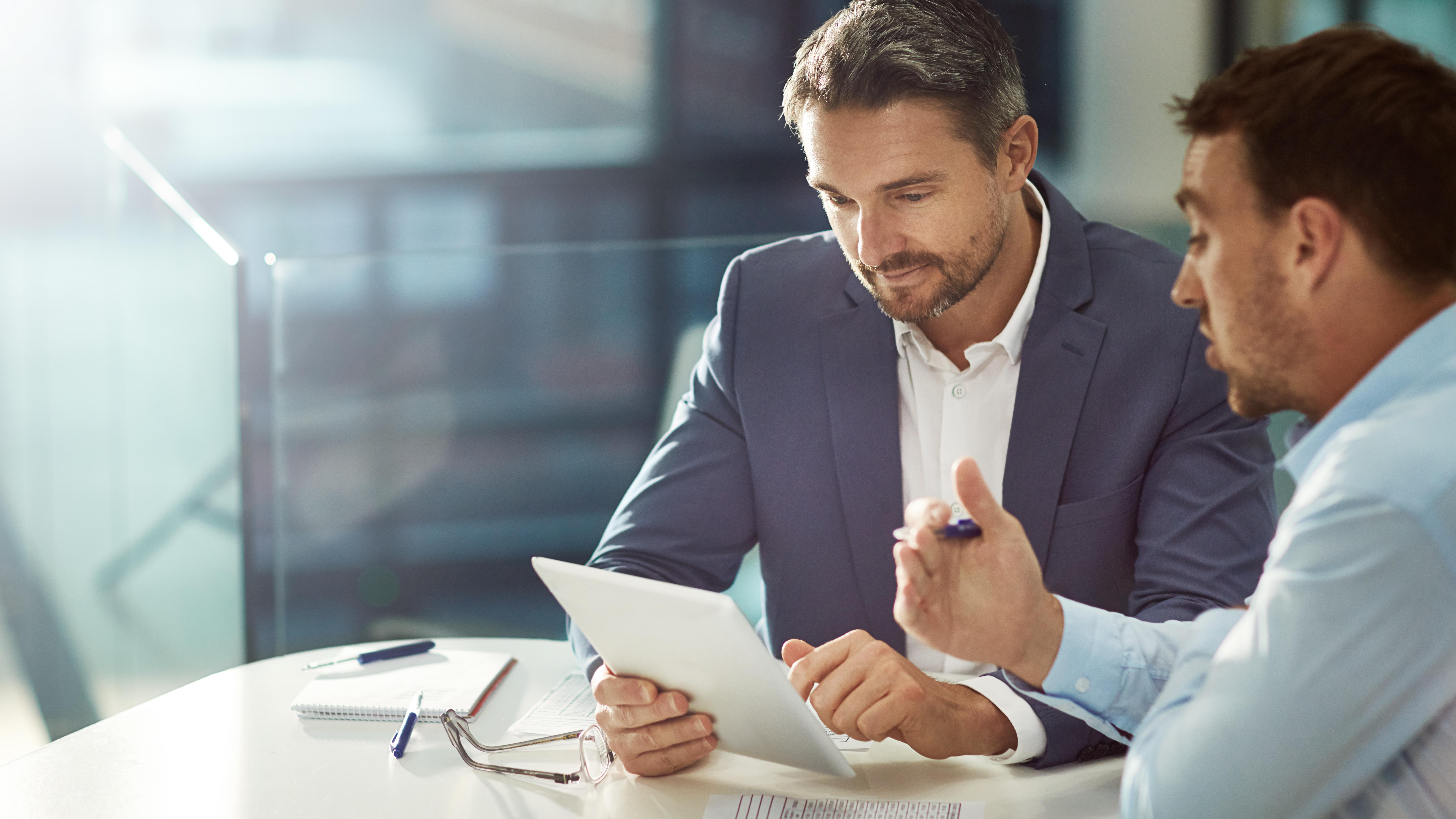Two employees with a tablet discussing sales