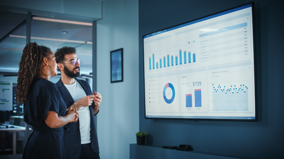 2 professionals reviewing marketing metrics on a screen