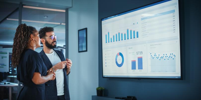 2 people discussing analytics shown on a screen