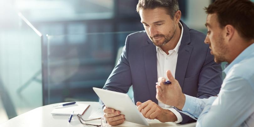 Two employees with a tablet discussing sales
