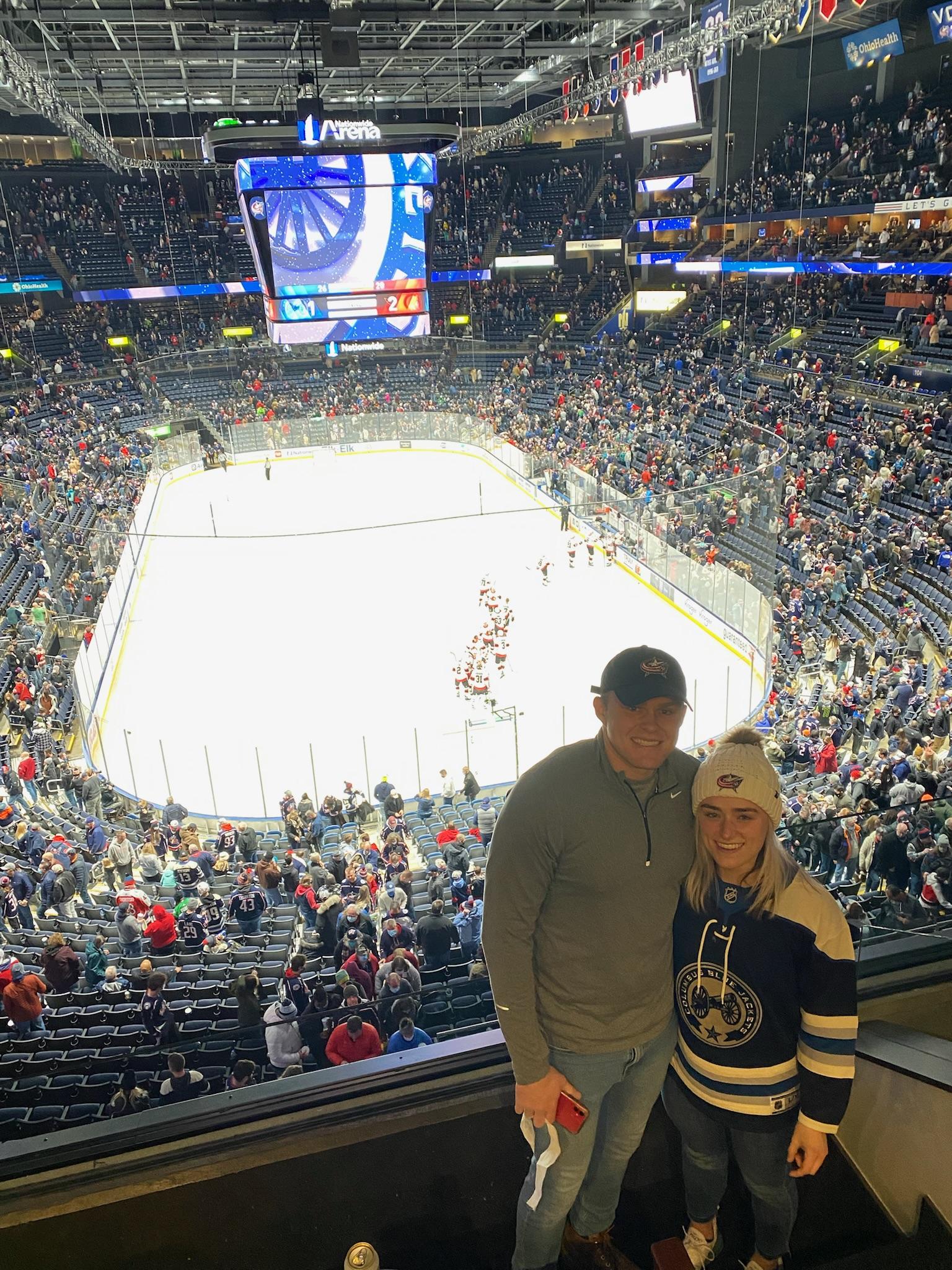 Two people in front of a hockey ice rink