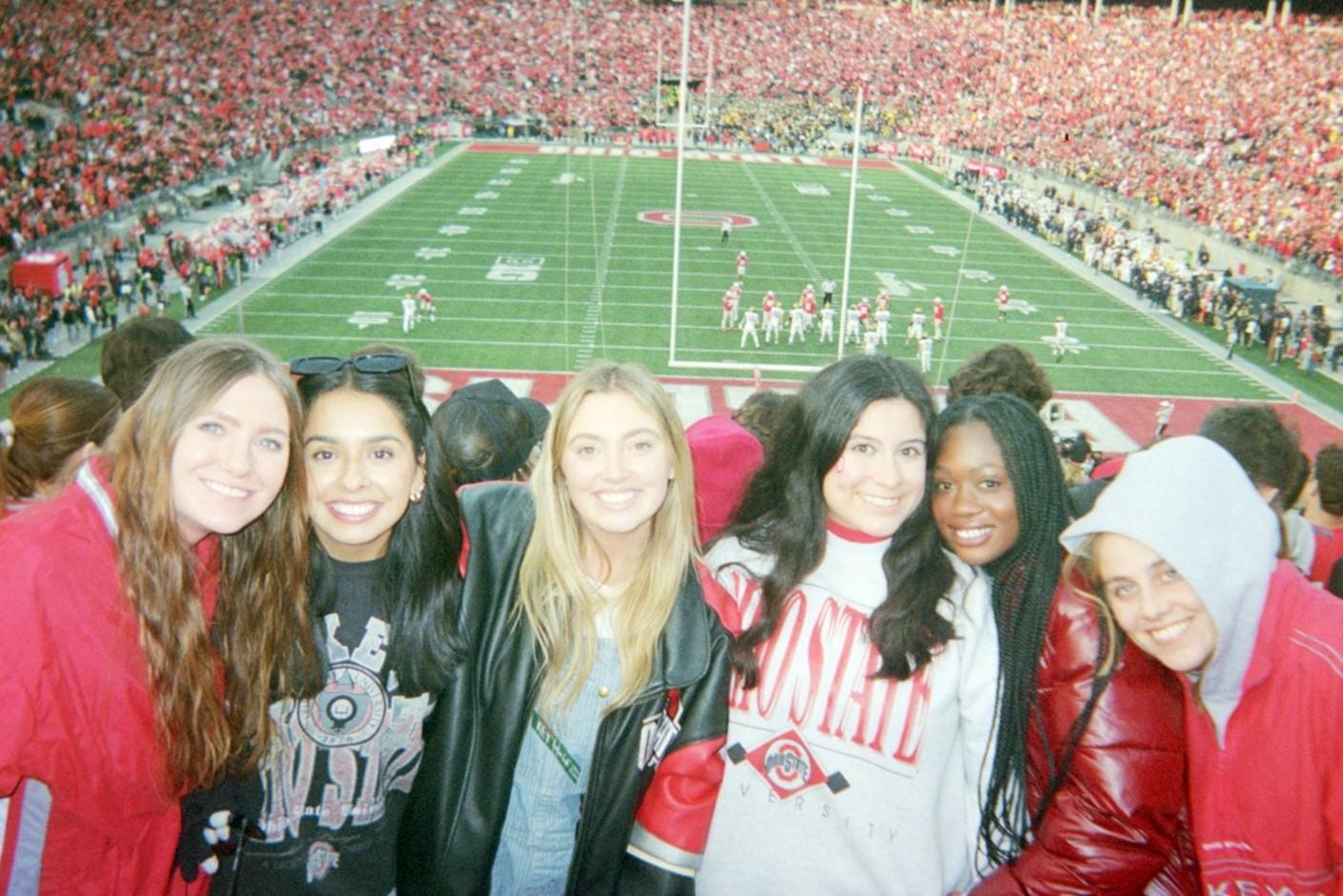 Group of friends at Ohio Stadium smiling for the camera with the football field behind them 