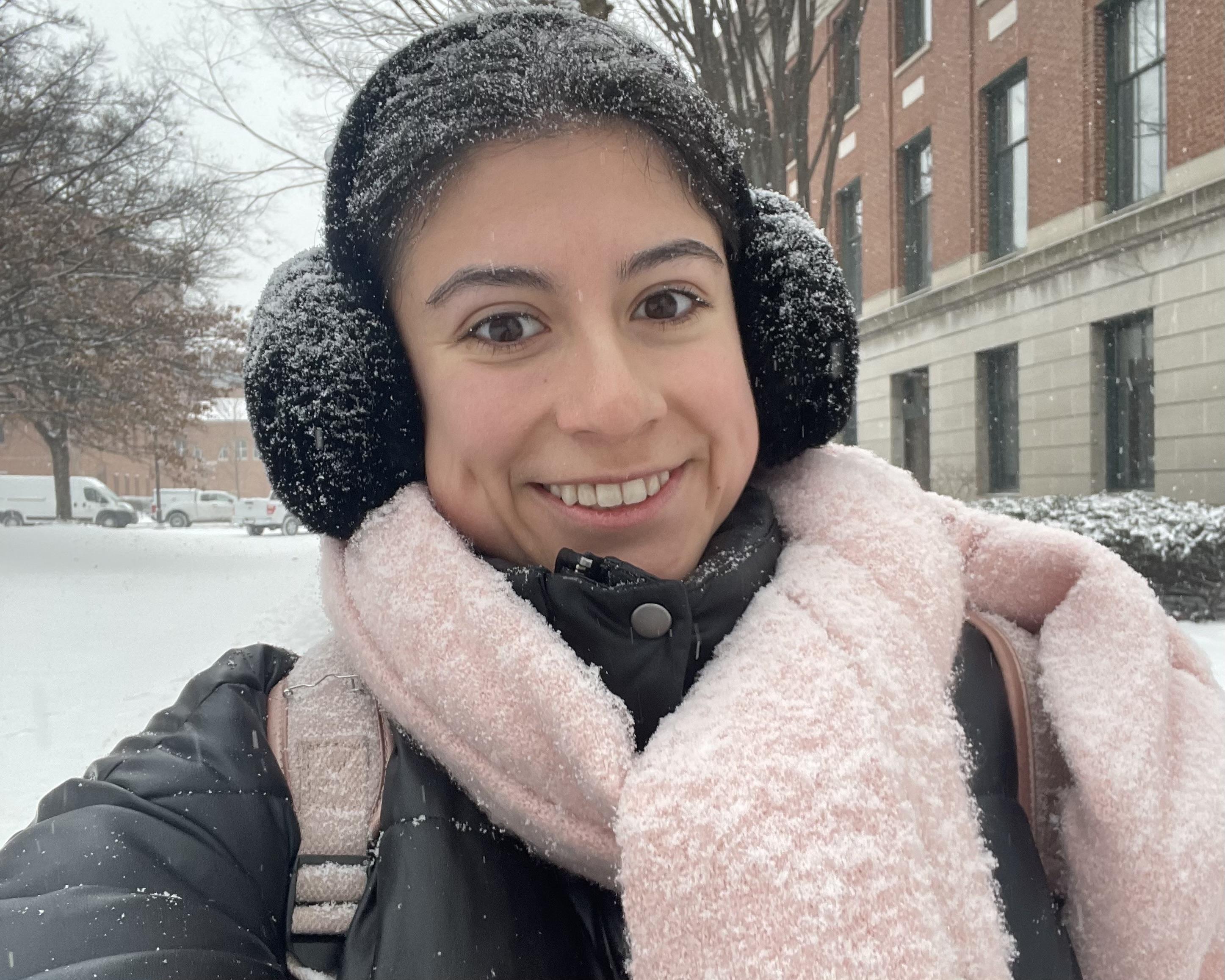 Student smiling while it is snowing outside 