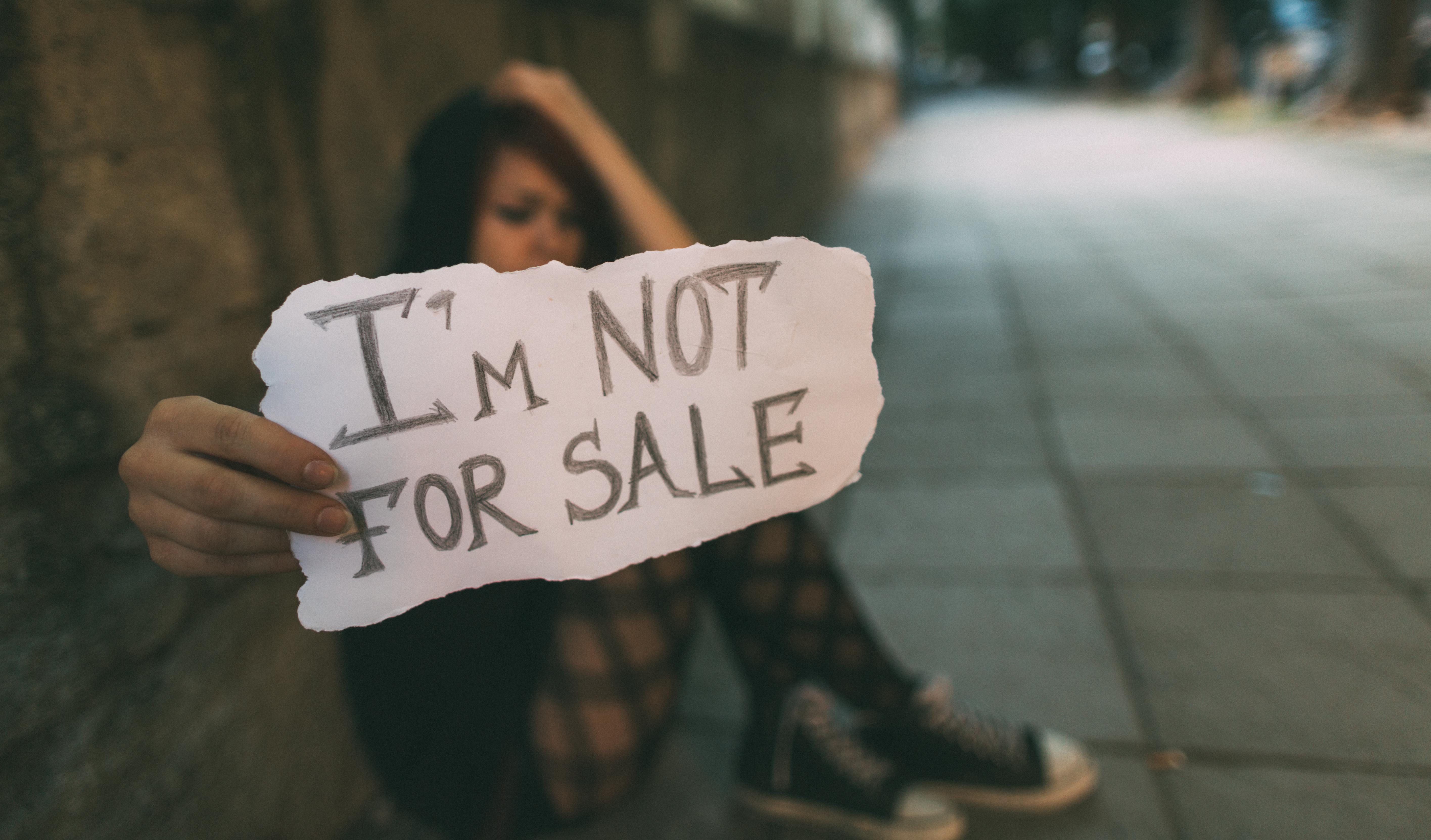 Girl on street with sign that reads "I'm Not For Sale"