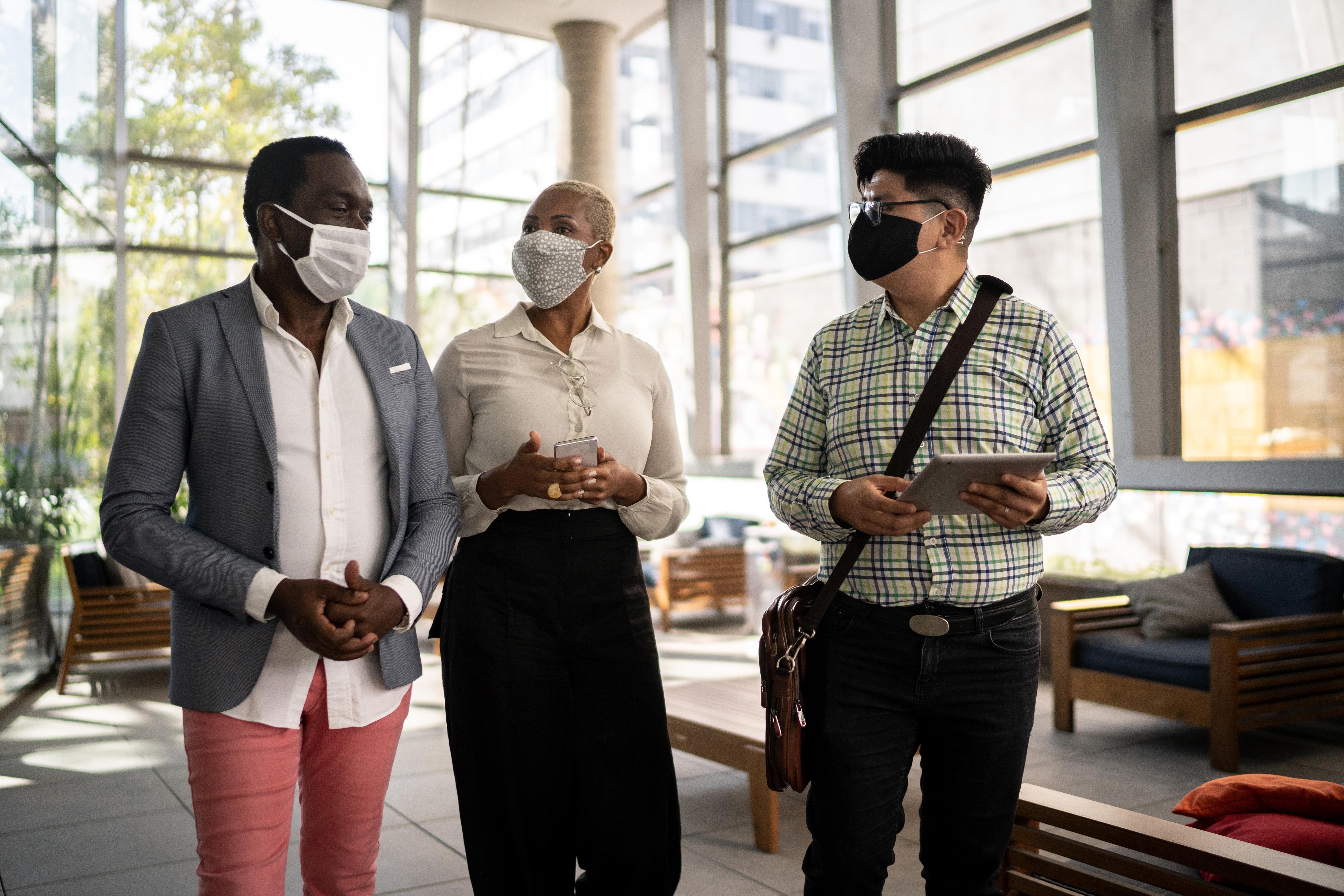Three people walking with masks on 