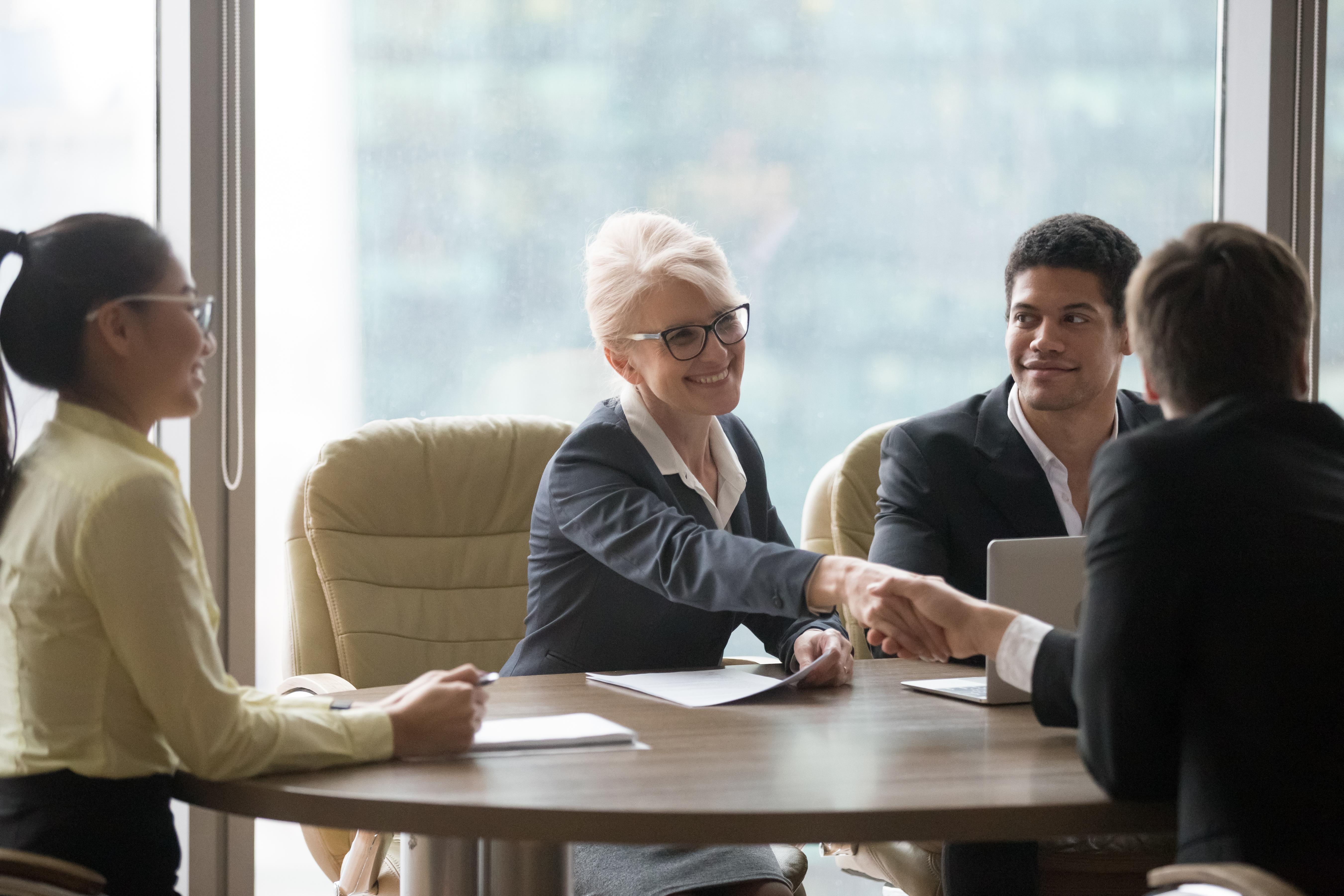 Female executive greeting someone at a table