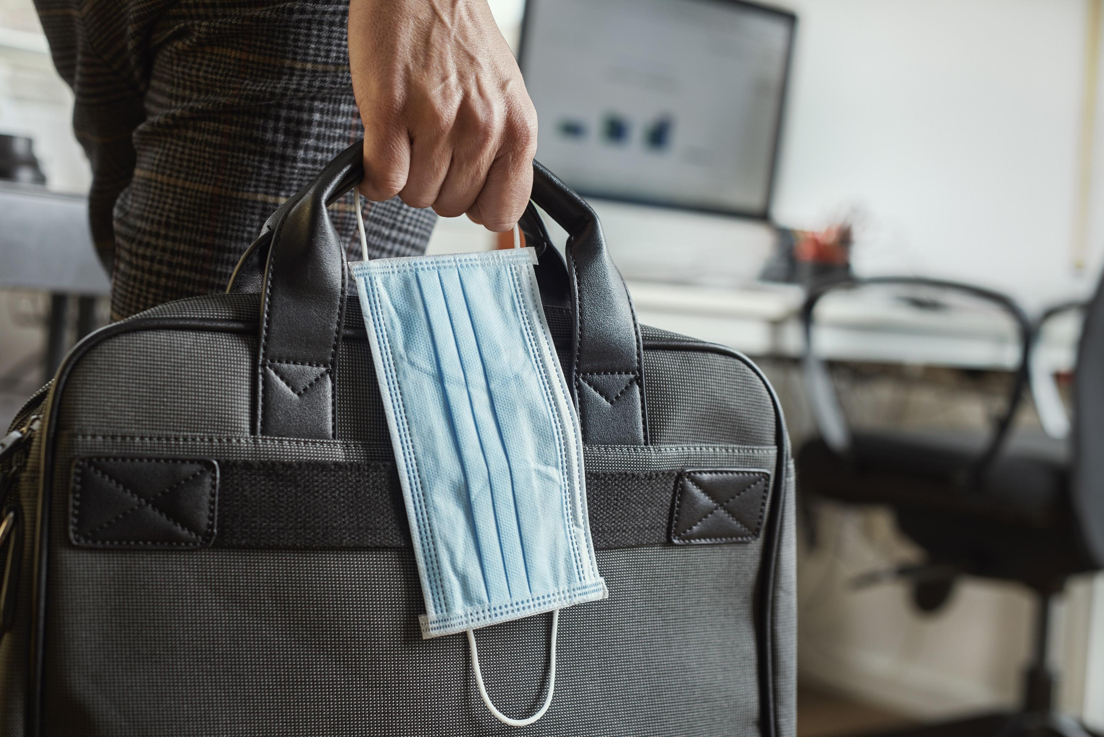 Man holding briefcase and mask