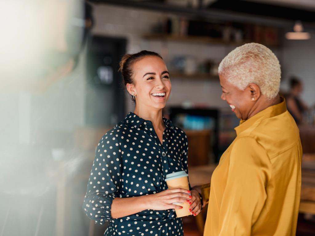 Two female coworkers talking happily 