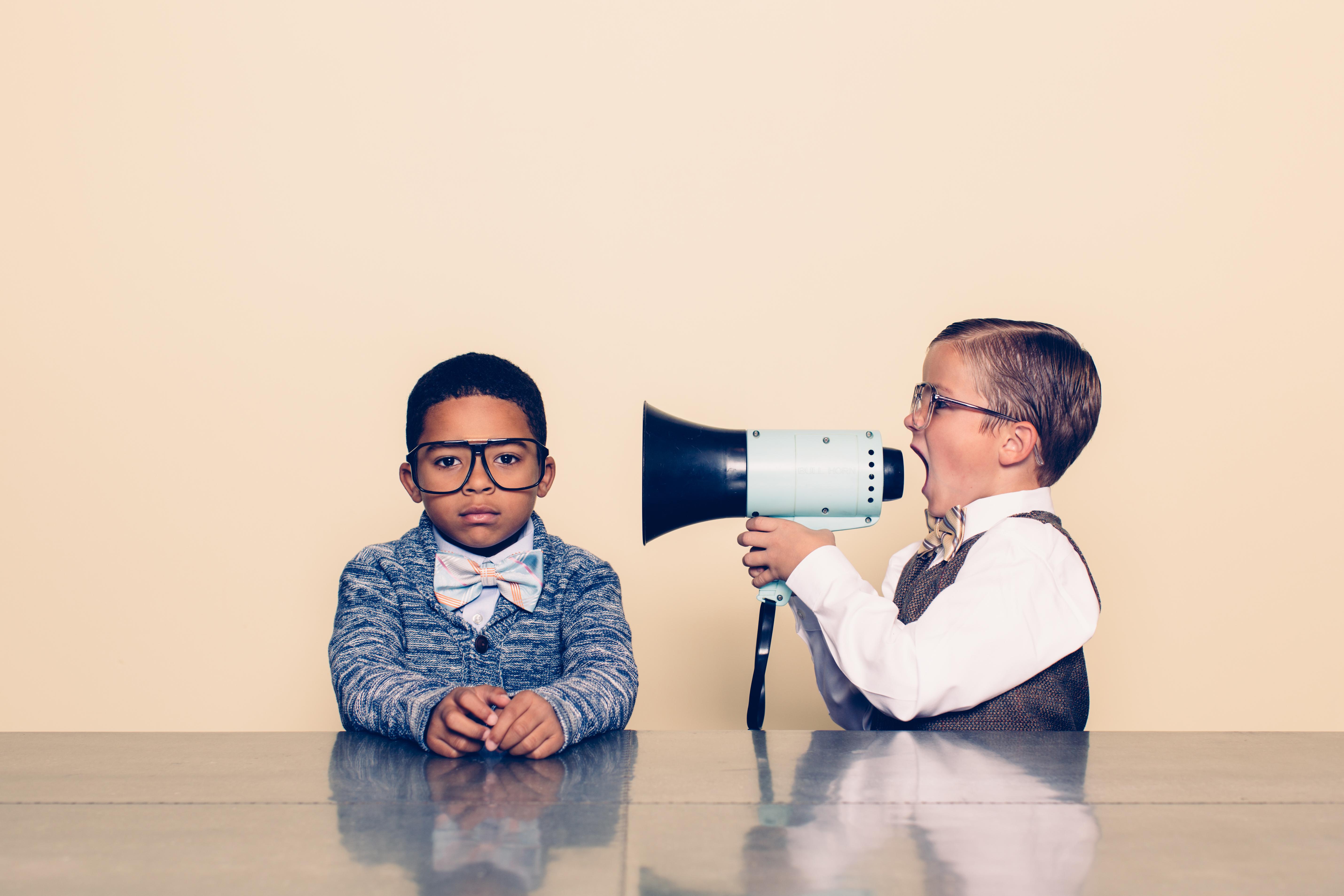 Young boy with megaphone tries to get another young boy to listen