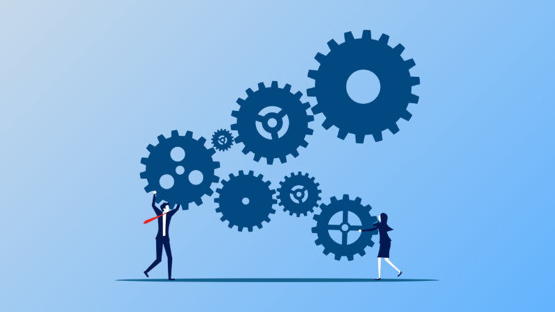 2 employees trying to prevent a bunch of connected gears from spinning