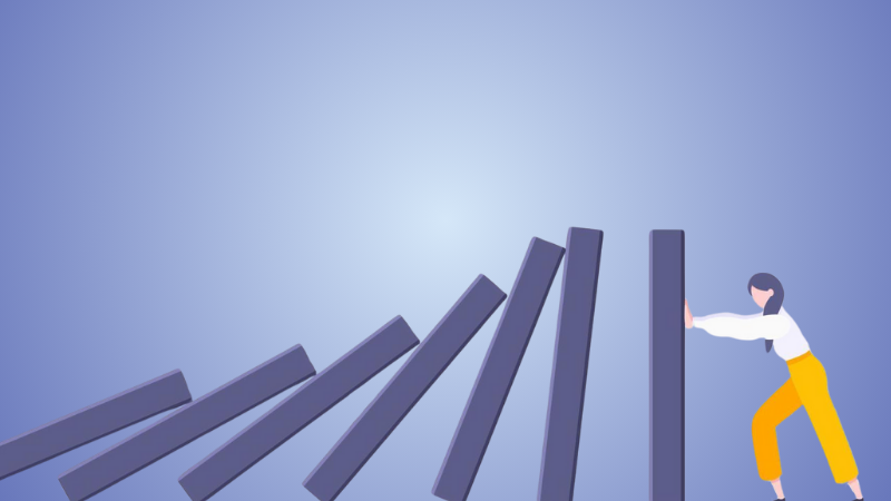 person pushing back against dominoes falling