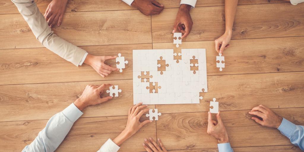 Team putting blank puzzle together 