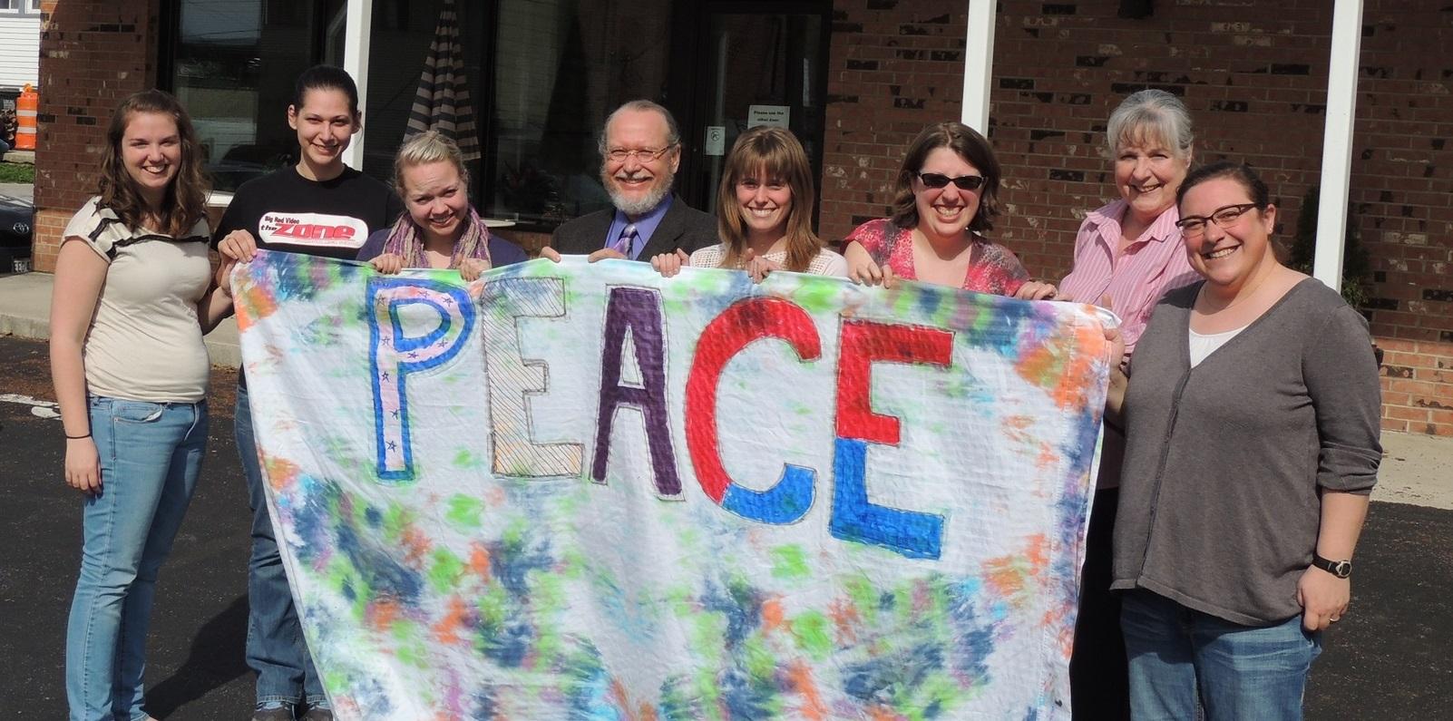 Group of diverse people that are holding a sign spelling "peace"