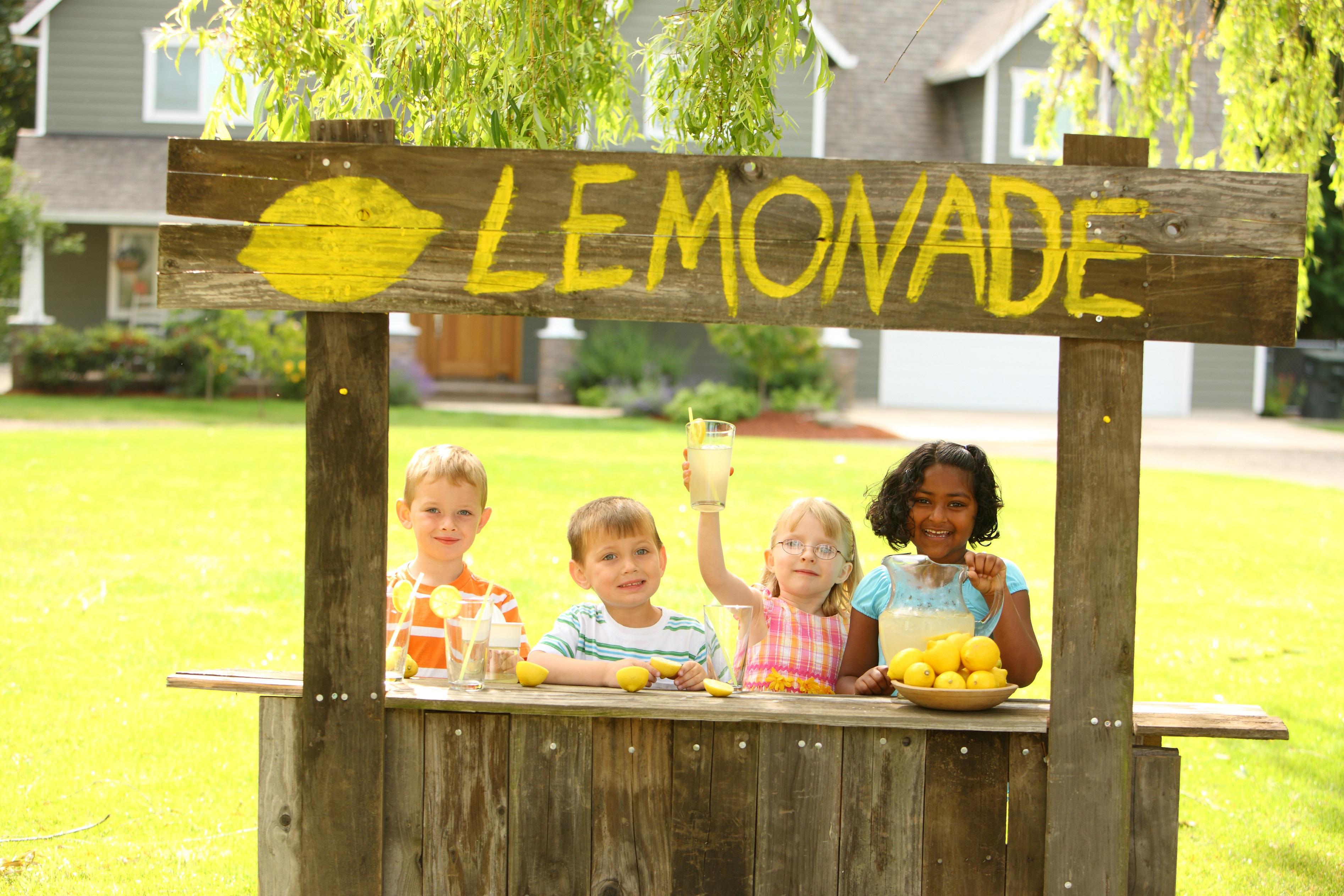 Four children smiling as they run a lemonade stand