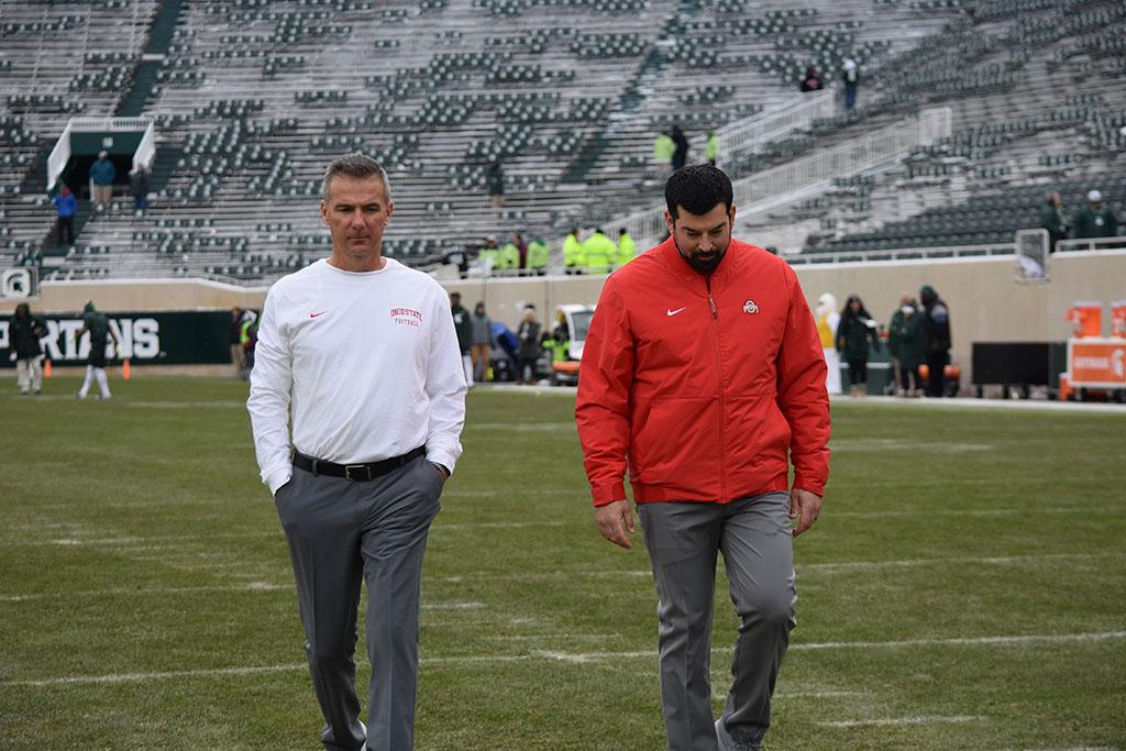 Urban Meyer and Ryan Day walking and talking together on football field