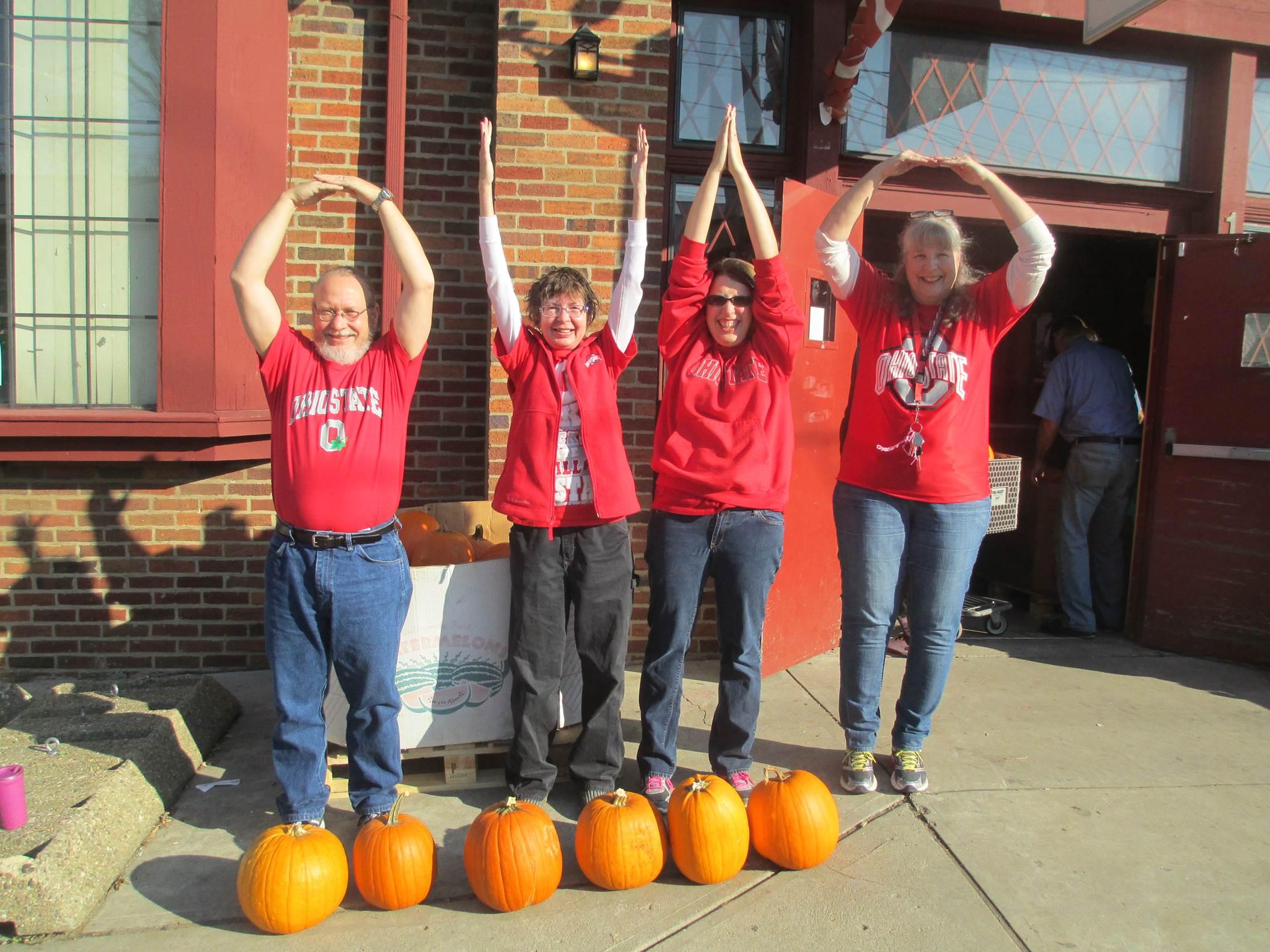 4 members of The Clintonville-Beechwold Community Resources Center spelling the word "OHIO" with their arms