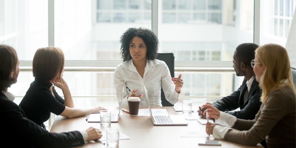 Employees directing attention to a black female coworker during a meeting