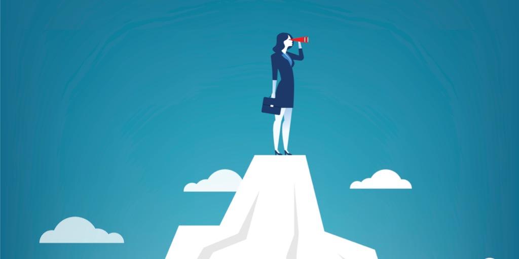 Women wearing business suit on top of mountain looking out with binoculars