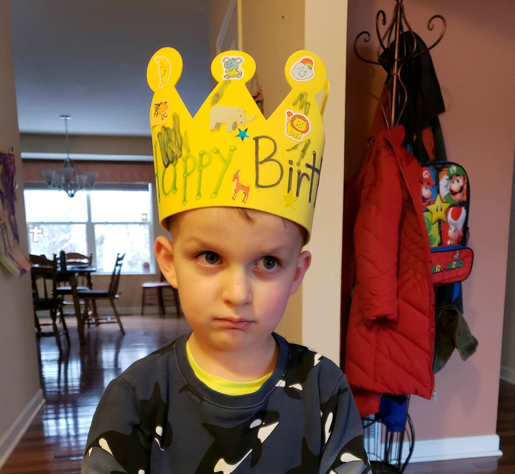 Kid wearing happy birthday crown frowning