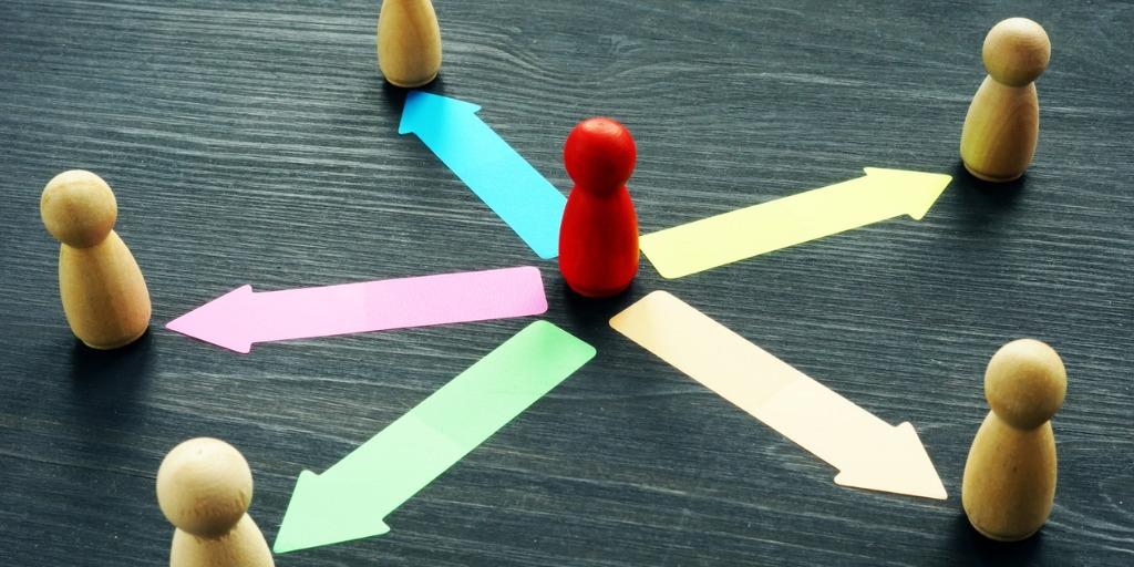 Brown wood pawns circling a red pawn in the center with arrows pointing from the red to the brown pawns