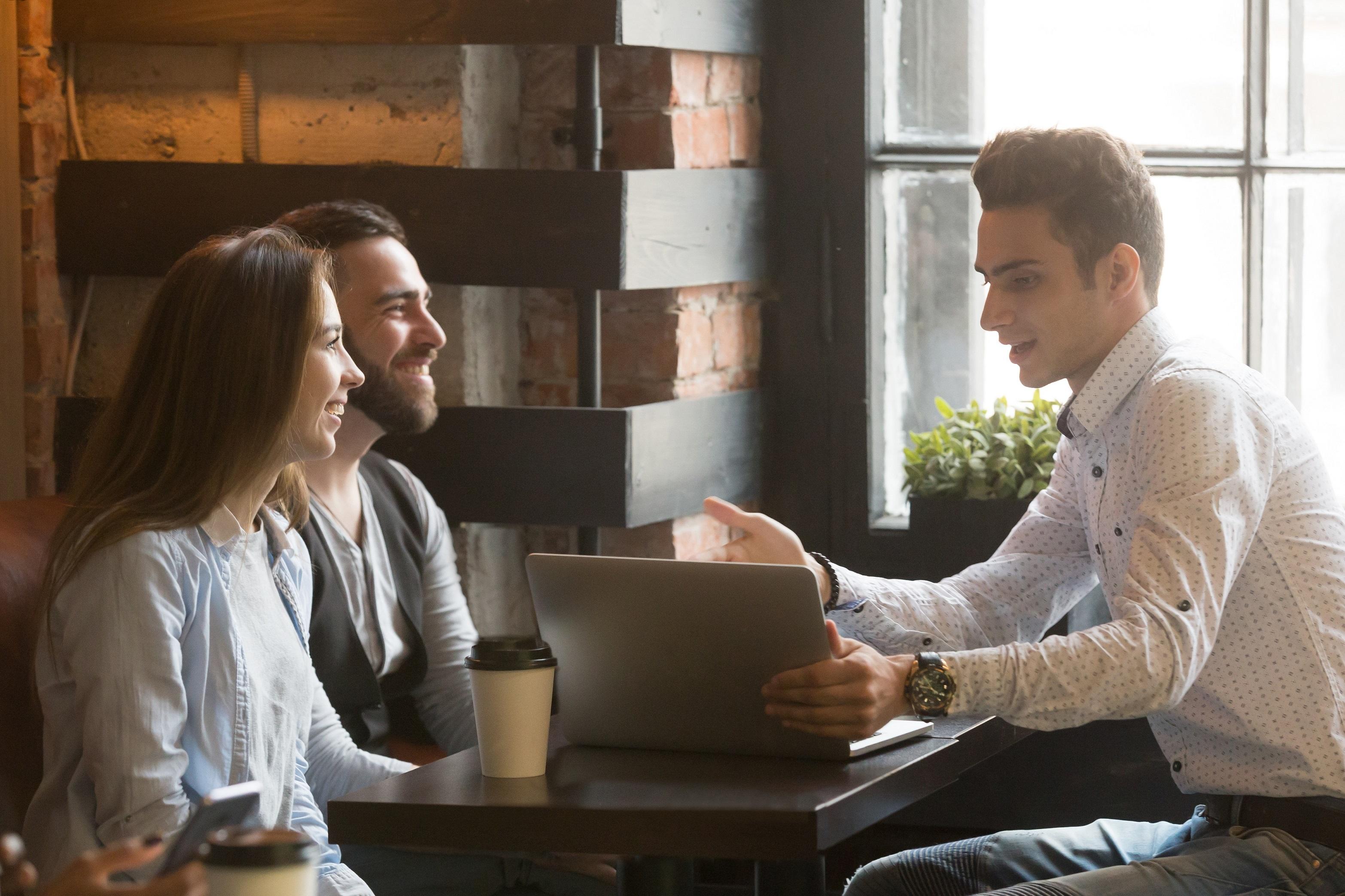 man talking to couple and showing laptop screen