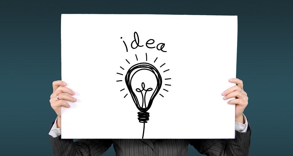 person holding sign that says "idea" with a lightbulb illustration on it