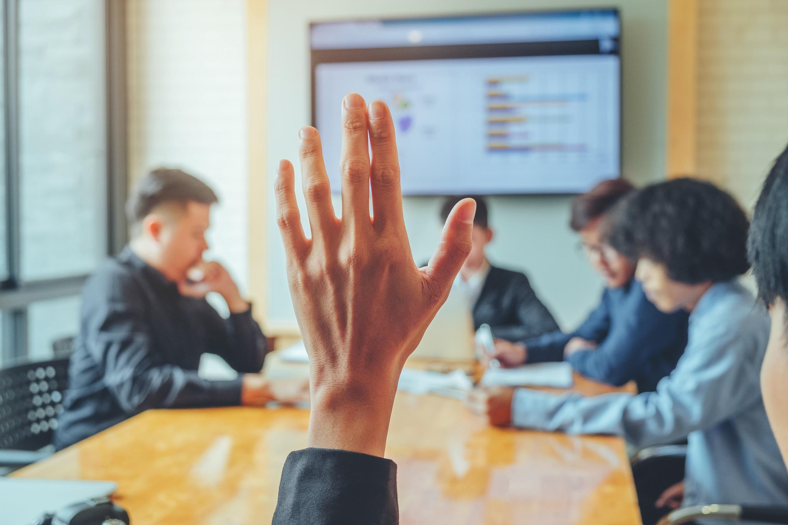 employee raising hand during meeting