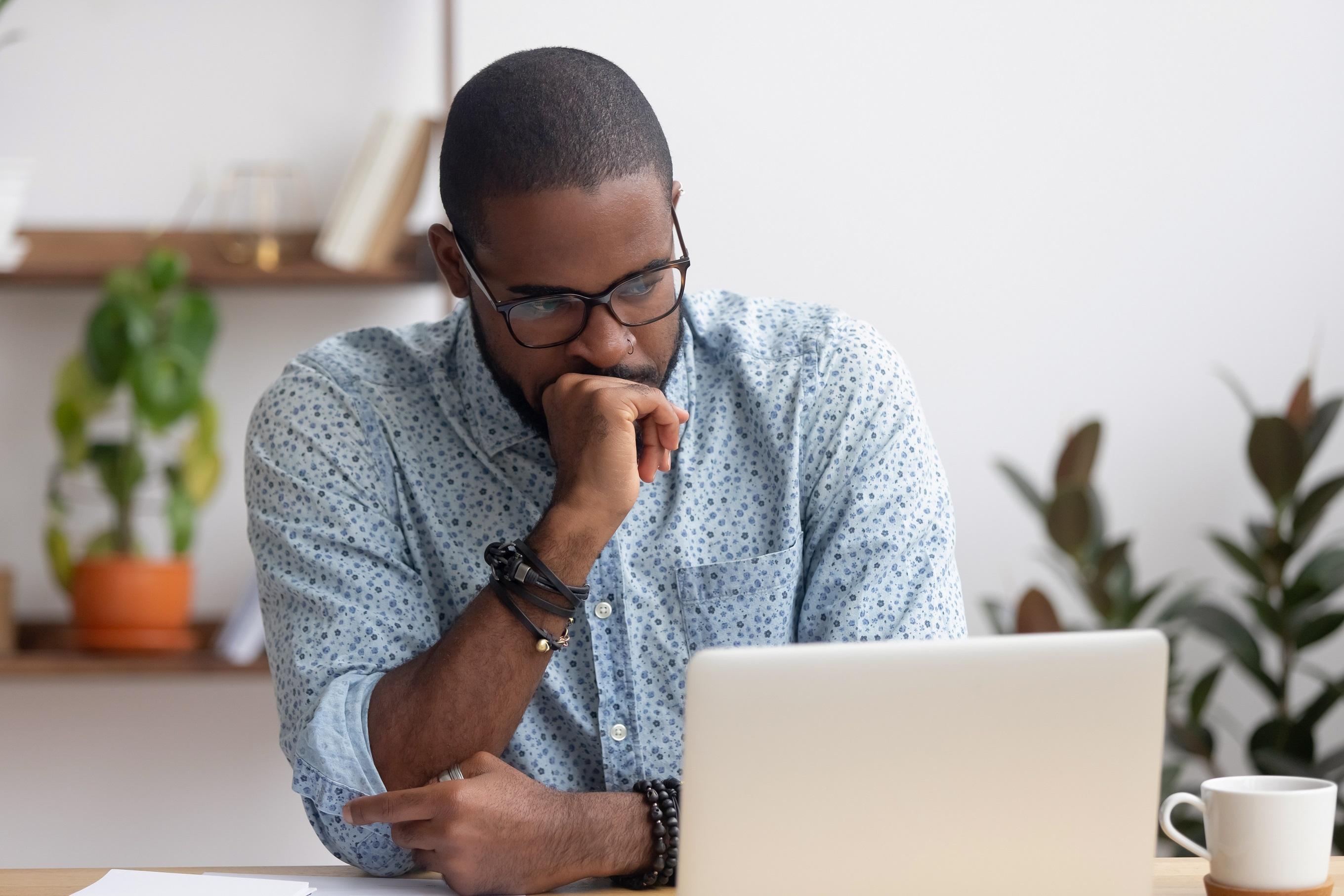 A man looking at his laptop, his face showing concern