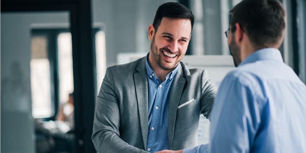 Two men smiling shaking hands