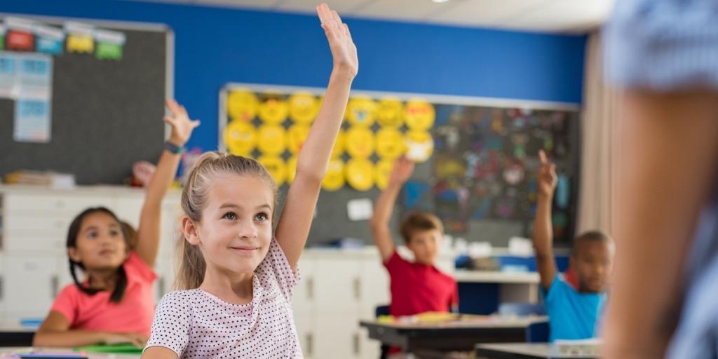 female elementary student raising hand in classroom