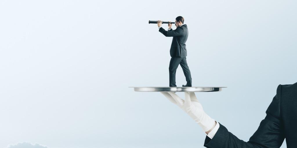 Butler carrying platter that has a tiny man in a suit looking through a telescope on it