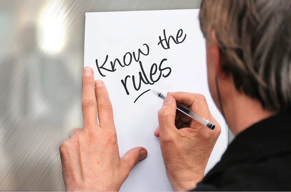 Man writing on a piece "Know the rules."