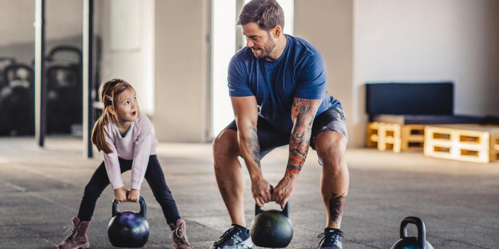 Father and daughter lifting weights at gym