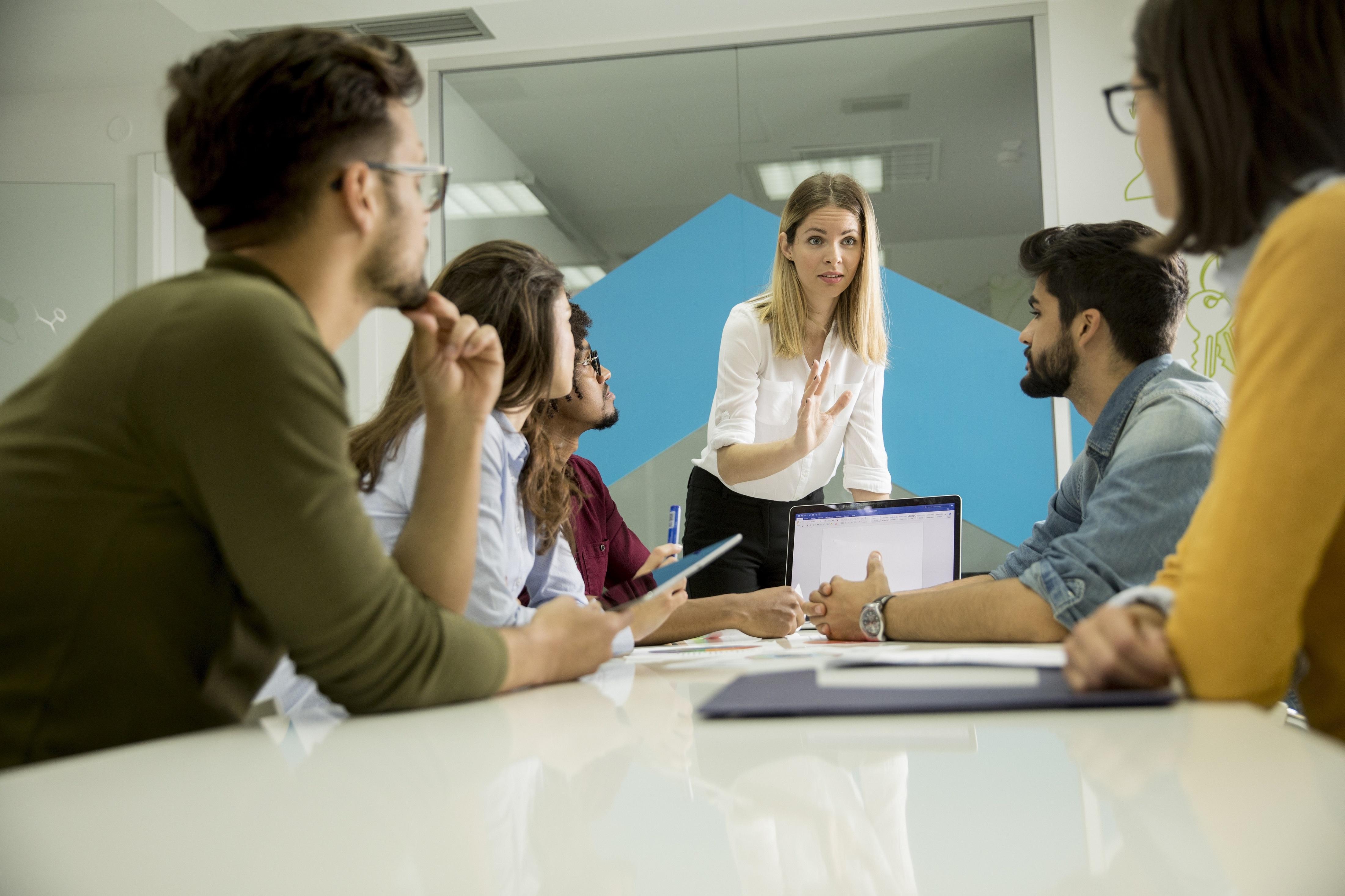 Women at front of table talking to the rest of the team seated 