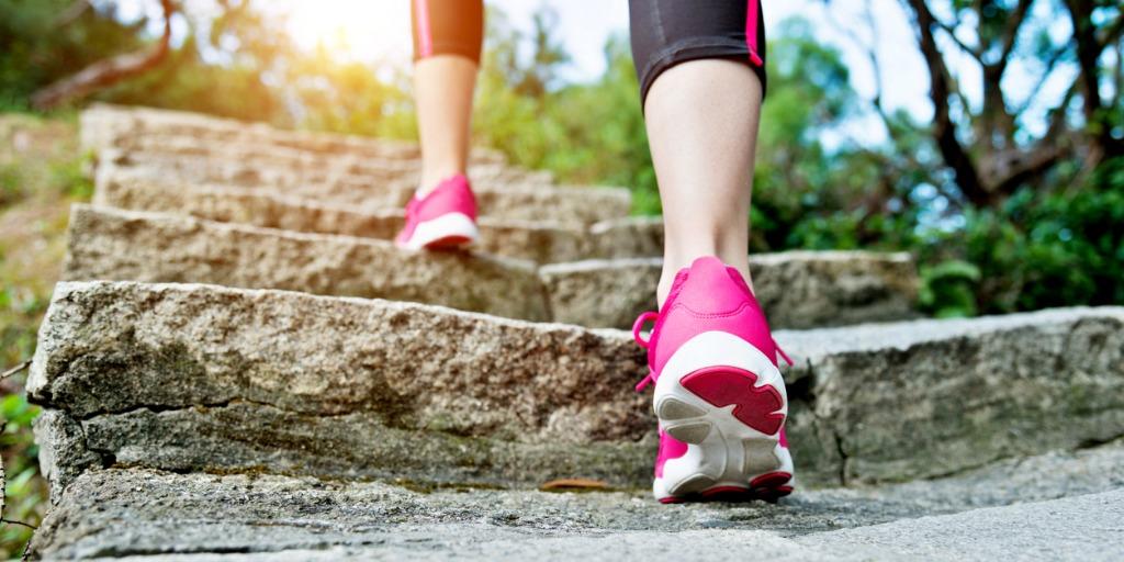 a person's feet wearing athletic shoes climbing stone stairs outdoors