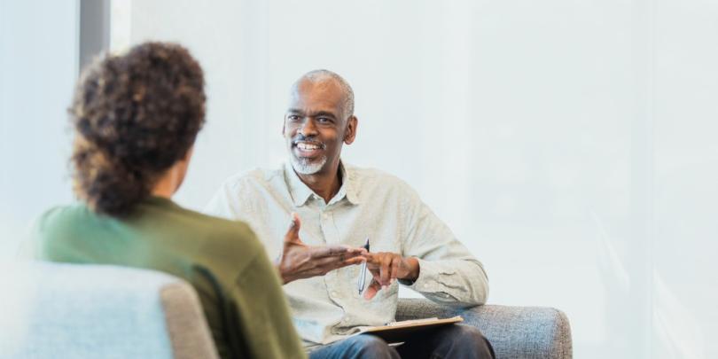 Unrecognizable woman listens as cheerful mentor gestures and speaks