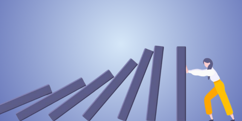 person pushing back against dominoes falling