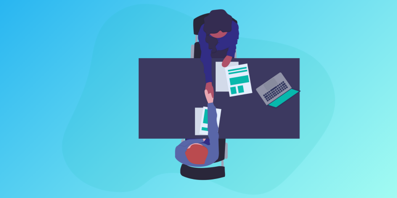 boss and employee shaking hands over a desk