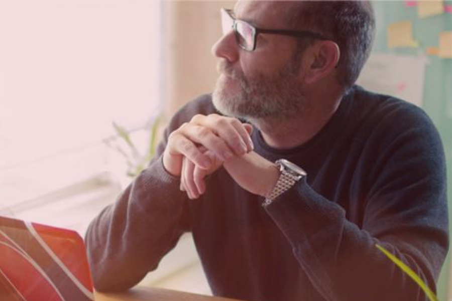 Man sitting at computer looking off in the distance in reflection