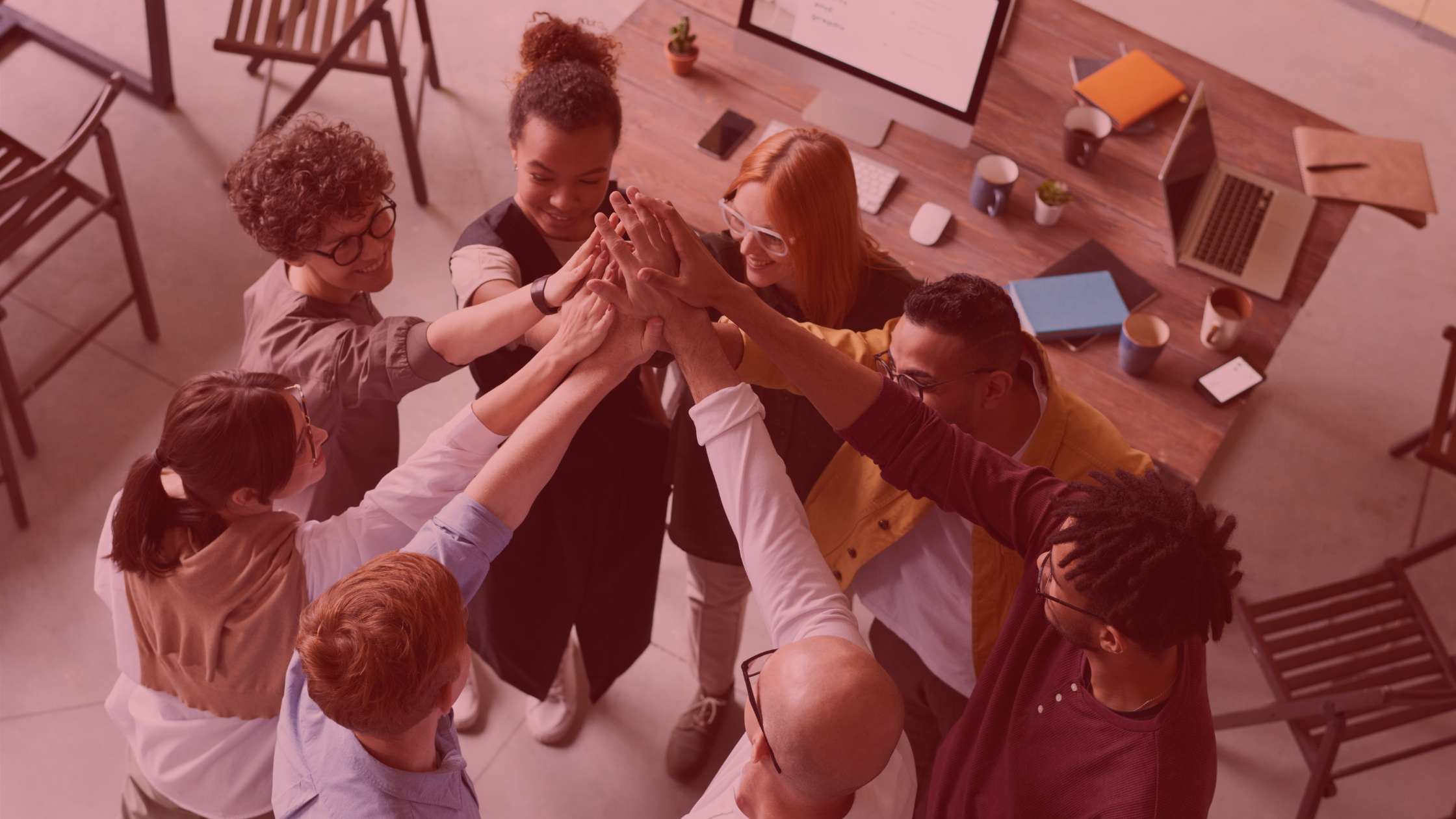 Diverse team huddle with everyones hands overlapping in the middle