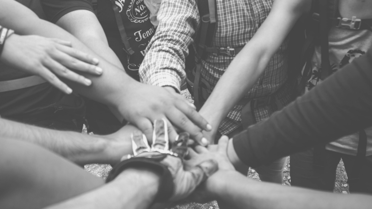 black and white image of hands coming together in a huddle