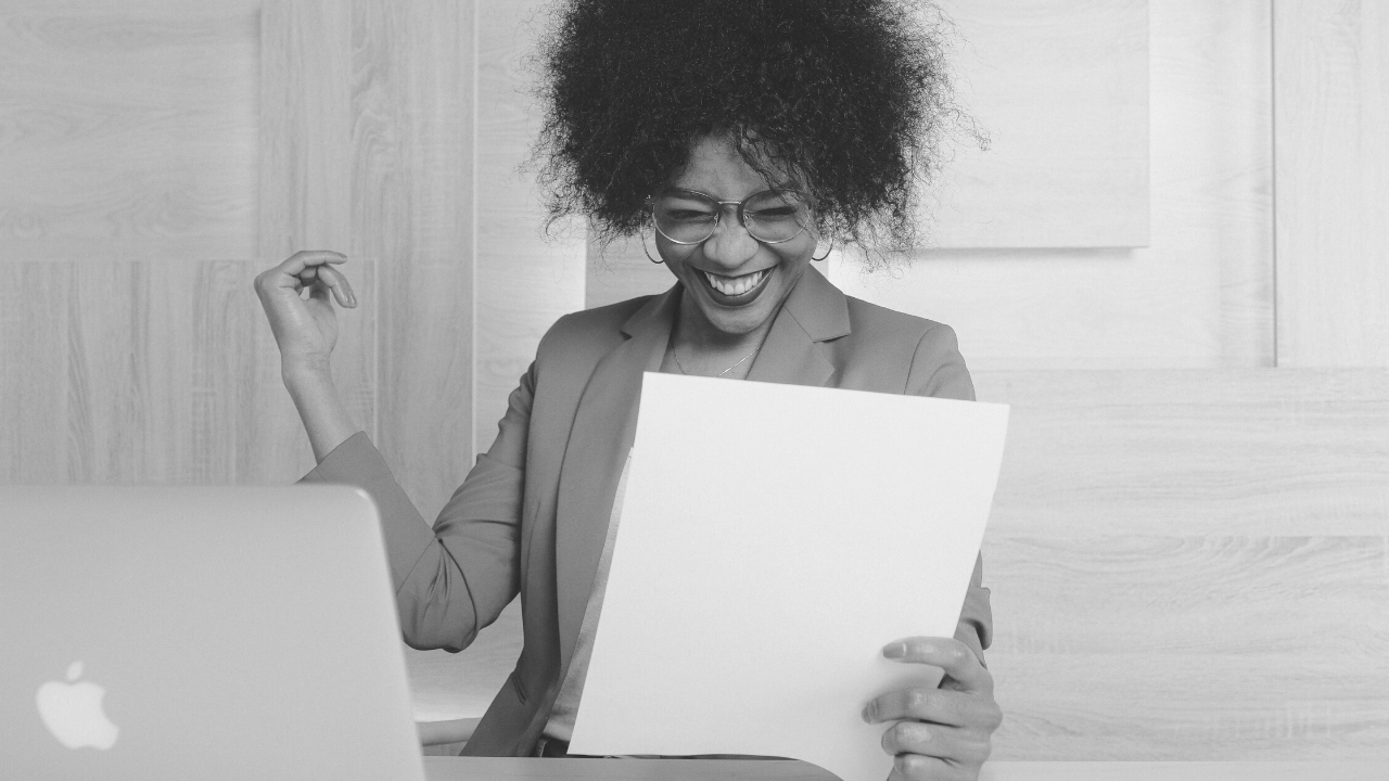 Black and white image of a woman sitting behind laptop