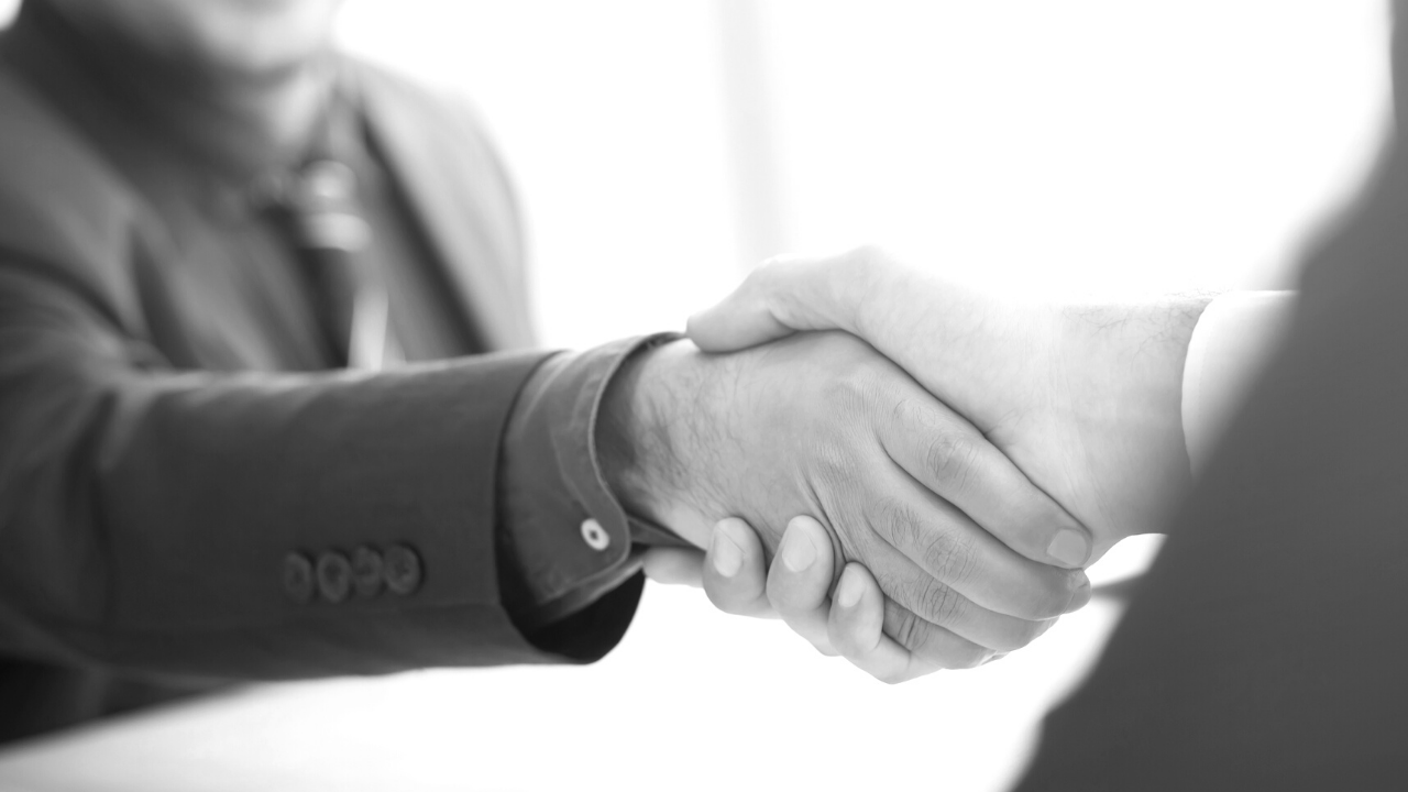Black and white image of two individuals shaking hands
