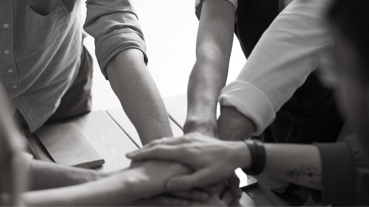 Group of people putting their hands together in center of circle 
